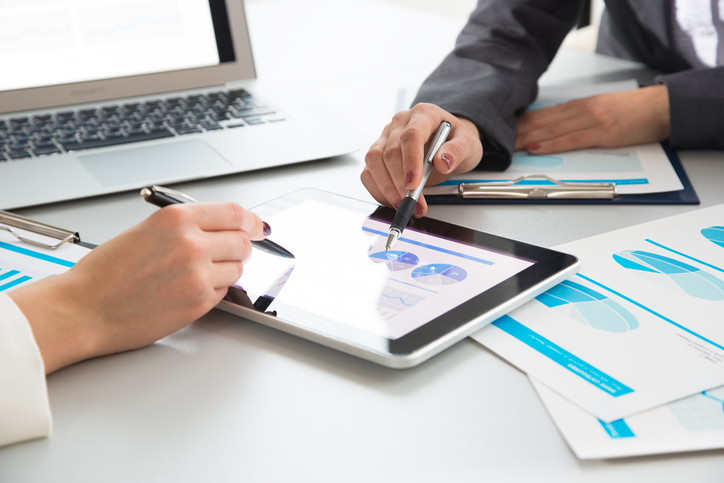 foto close de duas pessoas avaliando dados em um tablet, para realizar rateio de despesas.